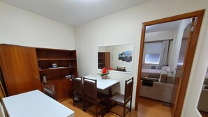 A compact kitchen with a dining area, wooden cabinets, and a small table with chairs. - Ap Copacabana 200m da praia - CP5 (Rio de Janeiro)