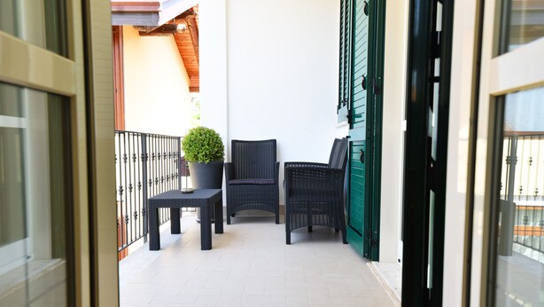 A balcony with wicker furniture, a potted plant, and a green door. - Chez Luke Apartment "Vintage" , 10 minutes from "Path of the God" (Pianillo)