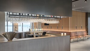 A modern reception area with a counter, seating, and a decorative light fixture. - Kirk Suites (Vejle)
