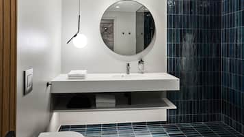 Un baño moderno con un espejo redondo, lavamanos blanco y paredes con azulejos azules.