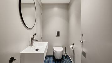Un baño pequeño y moderno con un lavamanos blanco, un inodoro y un espejo.