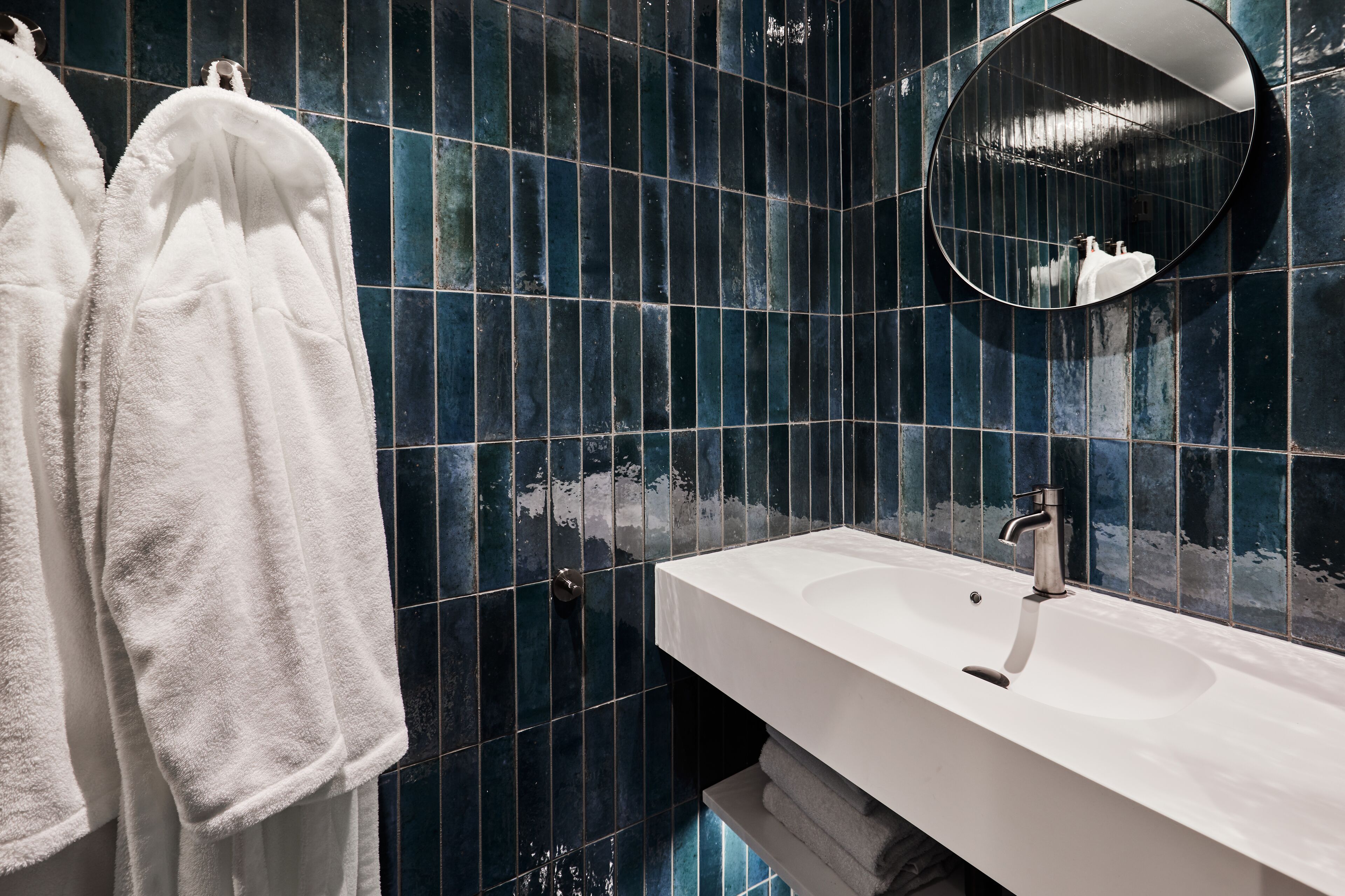 Ein Badezimmer mit einem weißen Waschbecken, einem Spiegel und Handtüchern an einem Wäscheständer.