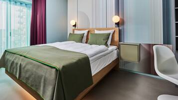 A modern hotel room with a large bed, a desk, and a chair.
