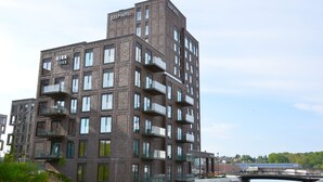 A multi-story hotel with balconies, a river view, and a bridge in the background. - Kirk Suites (Vejle)