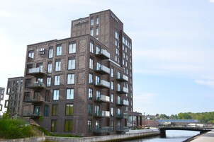 Un hotel de varios pisos con balcones, vista al río y un puente al fondo.