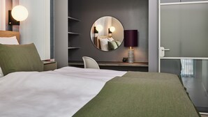 A hotel room with a large bed, a round mirror, a desk with a lamp, and a chair. - Kirk Suites (Vejle)