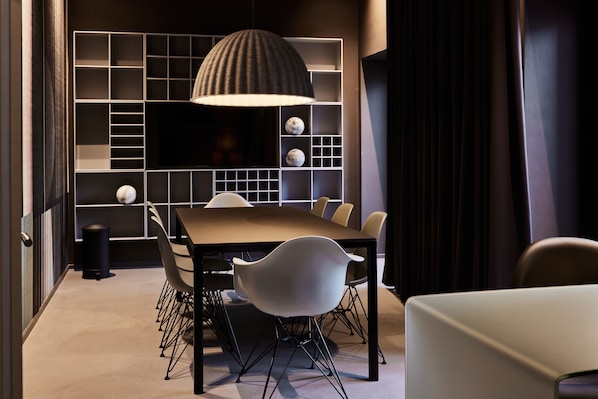 A modern dining area with a long table, white chairs, and a unique ceiling light fixture.