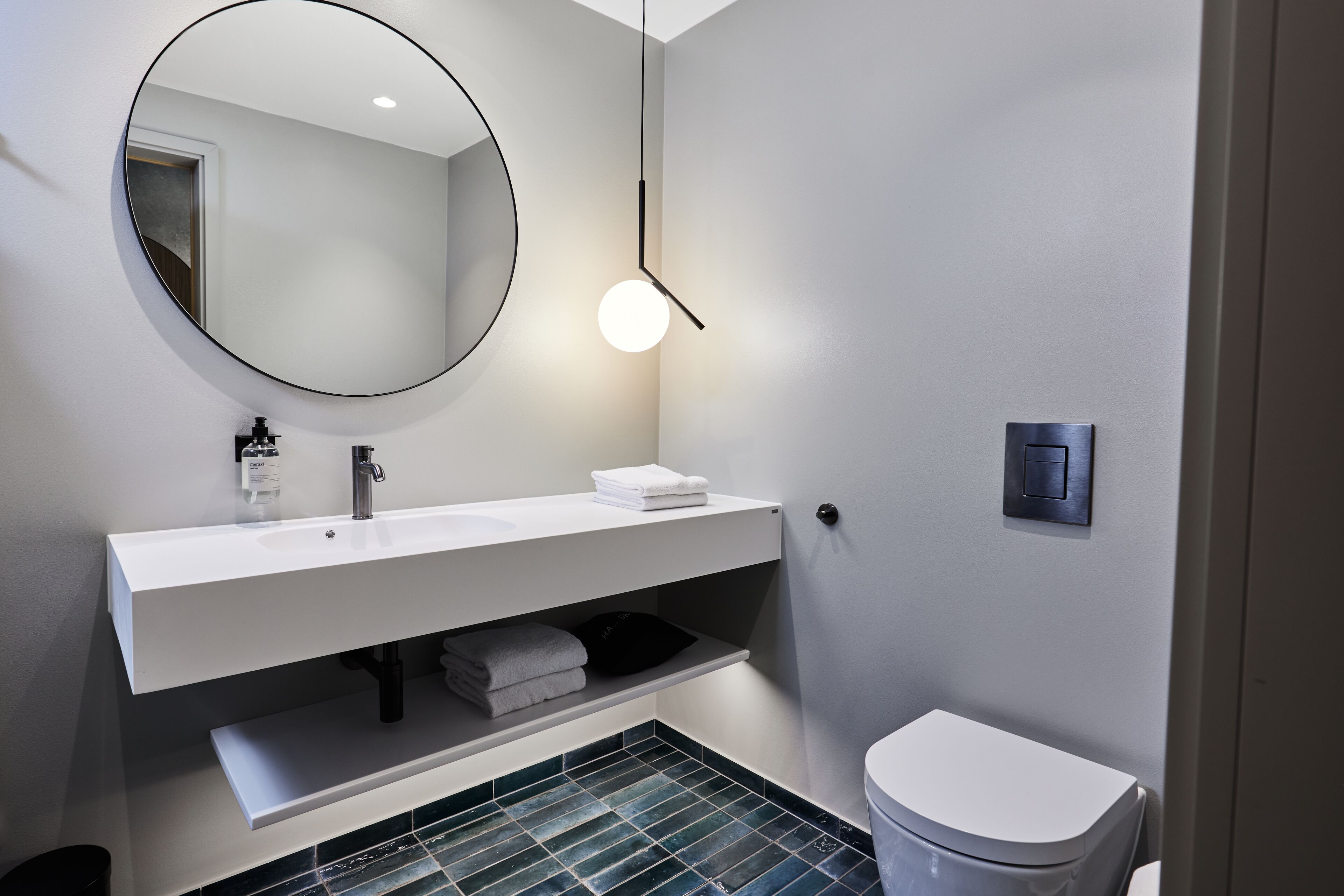 A modern bathroom with a white sink, mirror, and toilet.