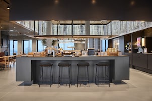 Una cocina moderna con una isla central, taburetes de bar y un techo alto con vistas a la ciudad.