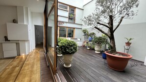 Un intérieur moderne avec un plancher en bois, un grand arbre en pot et un meuble blanc.