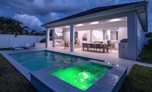 A modern house with a swimming pool, outdoor dining area, and a kitchen.
