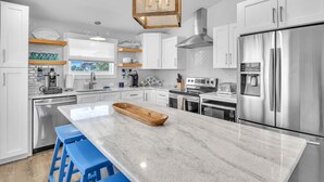 Une cuisine moderne avec des armoires blanches, des appareils en acier inoxydable et un grand îlot central en marbre.