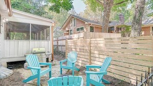 Ein Garten mit Holzterrasse, Grill und blauen Adirondack-Stühlen.