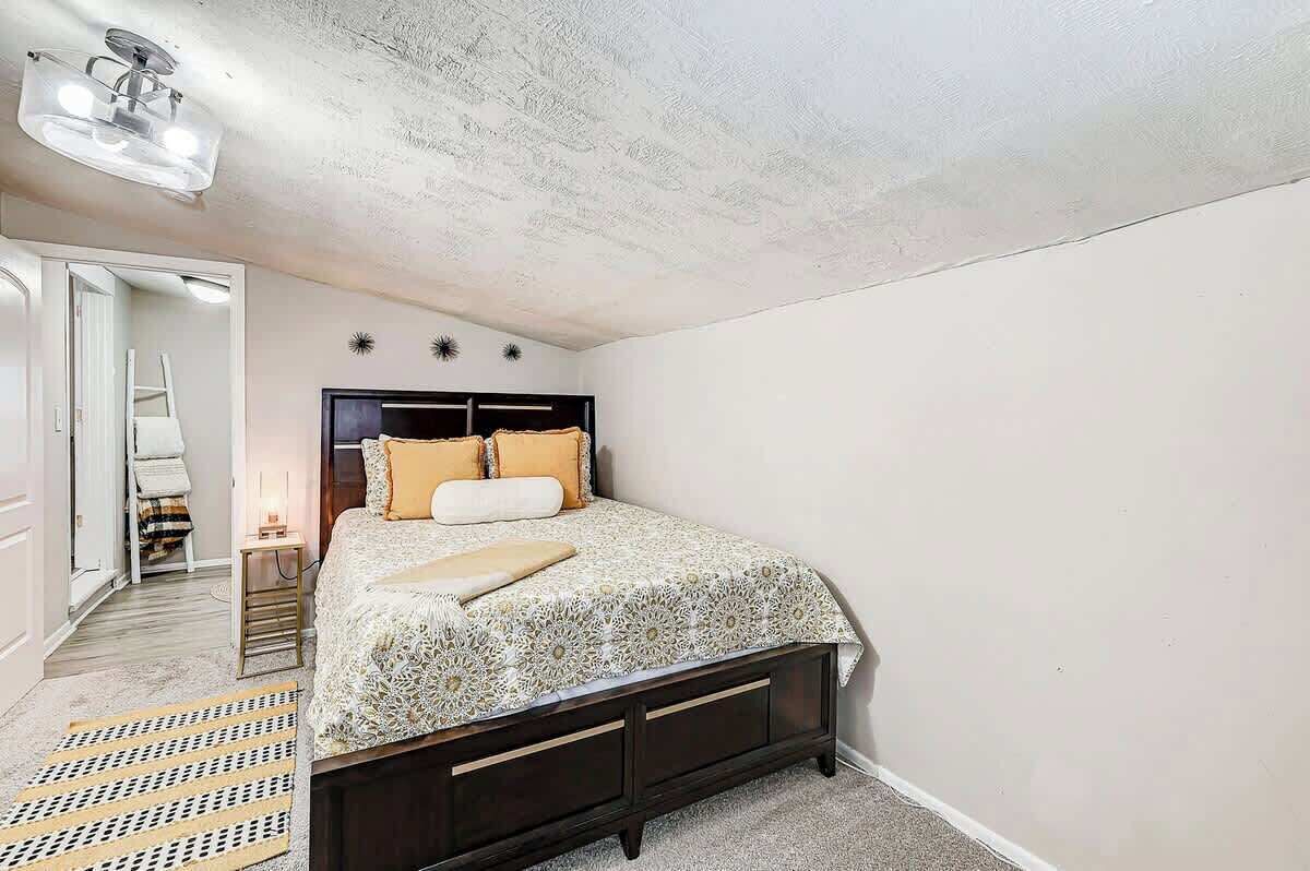 A bedroom with a bed, a nightstand, a lamp, and a ceiling light fixture.