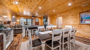 A wooden cabin interior with a dining area, kitchen, and living space. - Stunning Views,Hot Tub, Game Room,Zero Stair Entry (Cosby)