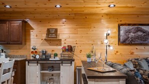 A cabin interior with wooden walls, a kitchen area, a dining table, and a sofa. - Stunning Views,Hot Tub, Game Room,Zero Stair Entry (Cosby)