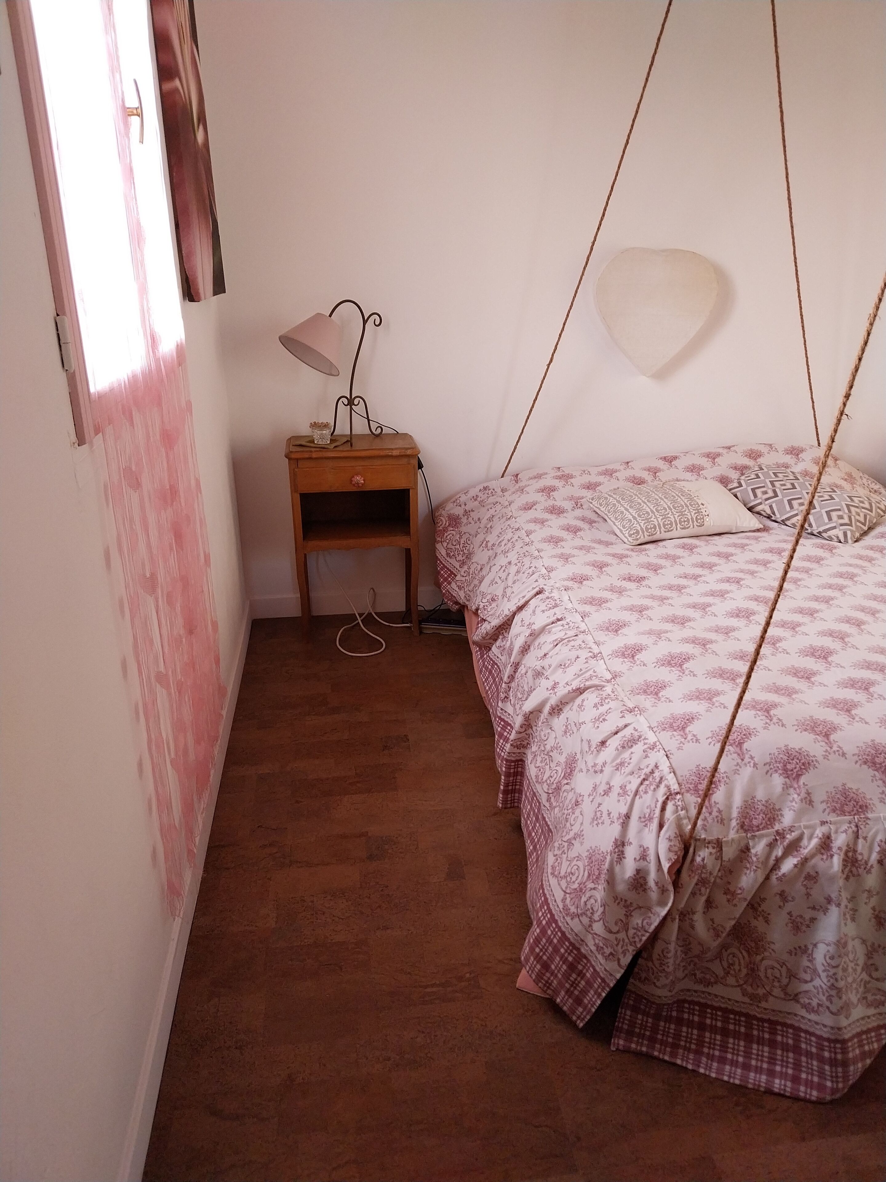 Ein Schlafzimmer mit einem Bett, einem Nachttisch, einer Lampe und einer Hängeschaukel.