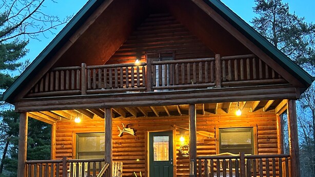 A log cabin with a porch, a front door, and a staircase leading to the entrance. - Family Friendly Deep Water Getaway - Close to Sand Valley Golf Courses (Nekoosa)