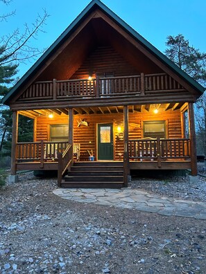 A log cabin with a porch, a front door, and a staircase leading to the entrance. - Family Friendly Deep Water Getaway - Close to Sand Valley Golf Courses (Nekoosa)