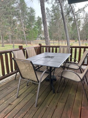 Una terraza de madera con una mesa y sillas, rodeada de árboles.