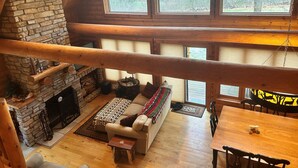 A cozy cabin interior with a stone fireplace, a sofa with a patterned throw, and a dining table with chairs. - Family Friendly Deep Water Getaway - Close to Sand Valley Golf Courses (Nekoosa)