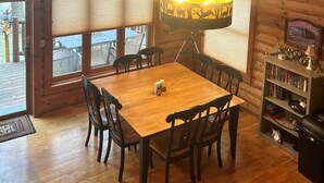A wooden dining area with a table and chairs, a hanging lamp, and a bookshelf. - Family Friendly Deep Water Getaway - Close to Sand Valley Golf Courses (Nekoosa)