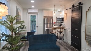 Una cocina moderna con armarios blancos, electrodomésticos de acero inoxidable y una puerta corredera negra.