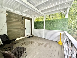 A covered porch with a door, a bench, and a yellow lamp post.