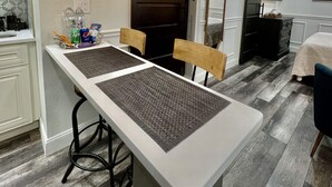 Una cocina moderna con una larga mesa de comedor, dos sillas, una lámpara colgante y una puerta de madera.