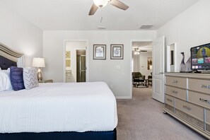 Une chambre à coucher avec un lit, une commode, un téléviseur et des tableaux encadrés accrochés au mur.