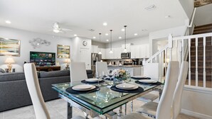 A modern kitchen with white cabinets, a glass dining table, and a ceiling fan. - Unforgettable Escape: Private Pool, PS5, Dreamy Resort, Moments from Disney (Kissimmee)