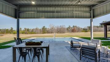 Un patio exterior con piscina, asientos y vistas del paisaje circundante.