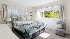 Une chambre à coucher avec un lit, des tables de chevet, une chaise et une fenêtre avec des rideaux.