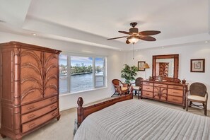 Quarto com cama grande, cômoda, penteadeira e ventilador de teto.