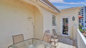 A balcony with a glass table and chairs, a door leading to a dining area, and a view of a high-rise building. - Fort Lauderdale Yacht & Beach Club 411 (Fort Lauderdale)