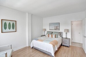 Ein Schlafzimmer mit Bett, Nachttischen, einem Sessel und Bildern an den Wänden.