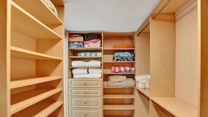 A walk-in closet with multiple shelves and drawers, some containing folded clothes and storage boxes.