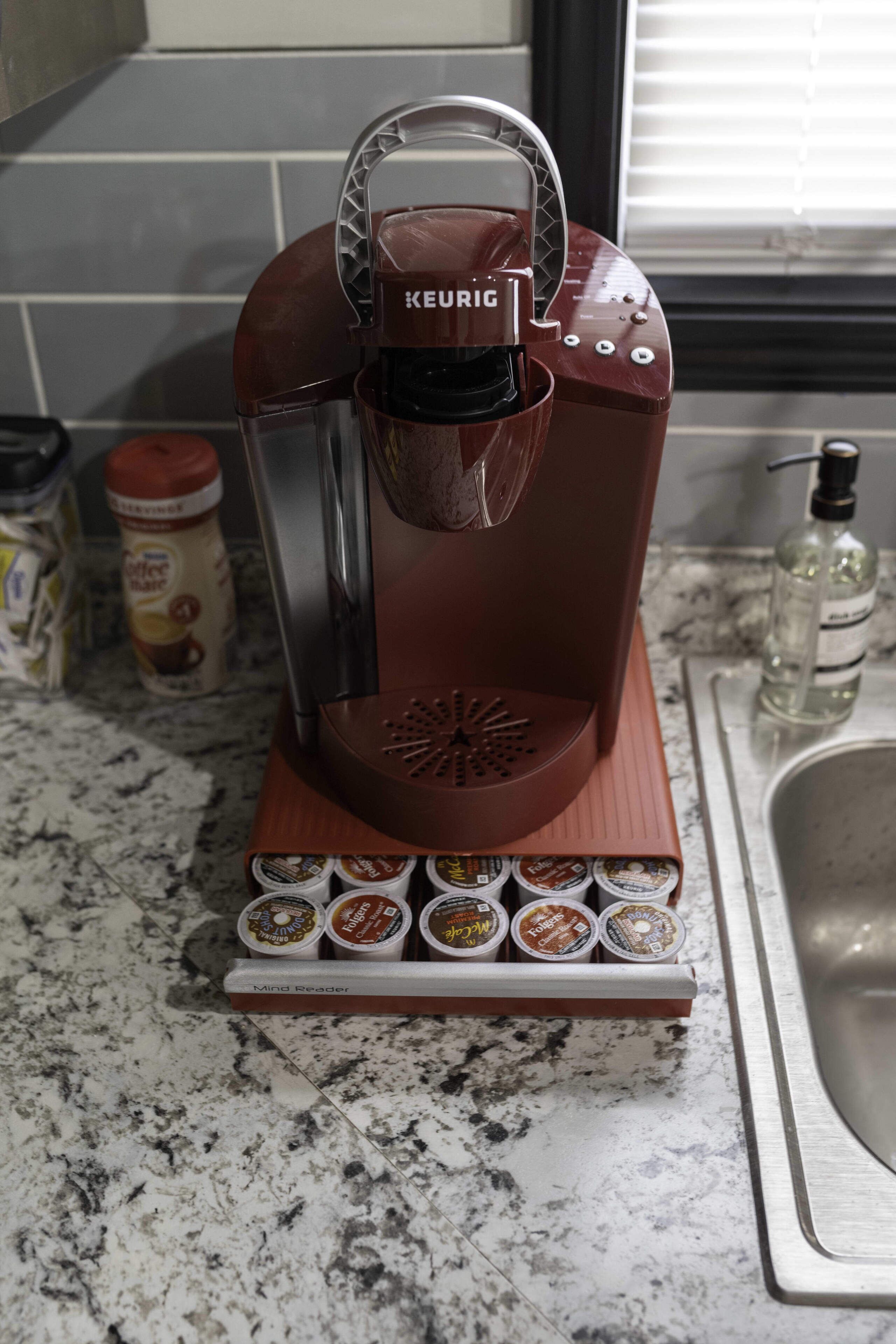 Une machine à café Keurig avec un distributeur de dosettes de café, posée sur un plan de travail de cuisine.