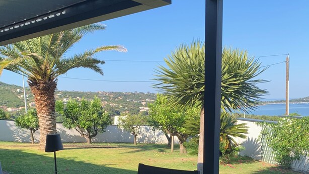 Un área de comedor al aire libre con una mesa, sillas y vistas al mar y vegetación.