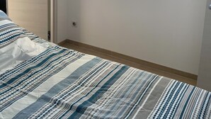 Un dormitorio con una cama, una ventana que da a zonas verdes y una puerta.