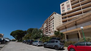 A parking lot with several cars, a multi-story building with balconies, and a clear blue sky. - Chapelle des Grecs - 1km de la plage (Ajaccio)