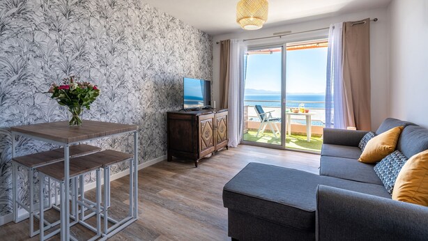 A modern living room with a sofa, a TV, a wooden table, and a balcony with a view of the sea. - Chapelle des Grecs - 1km de la plage (Ajaccio)