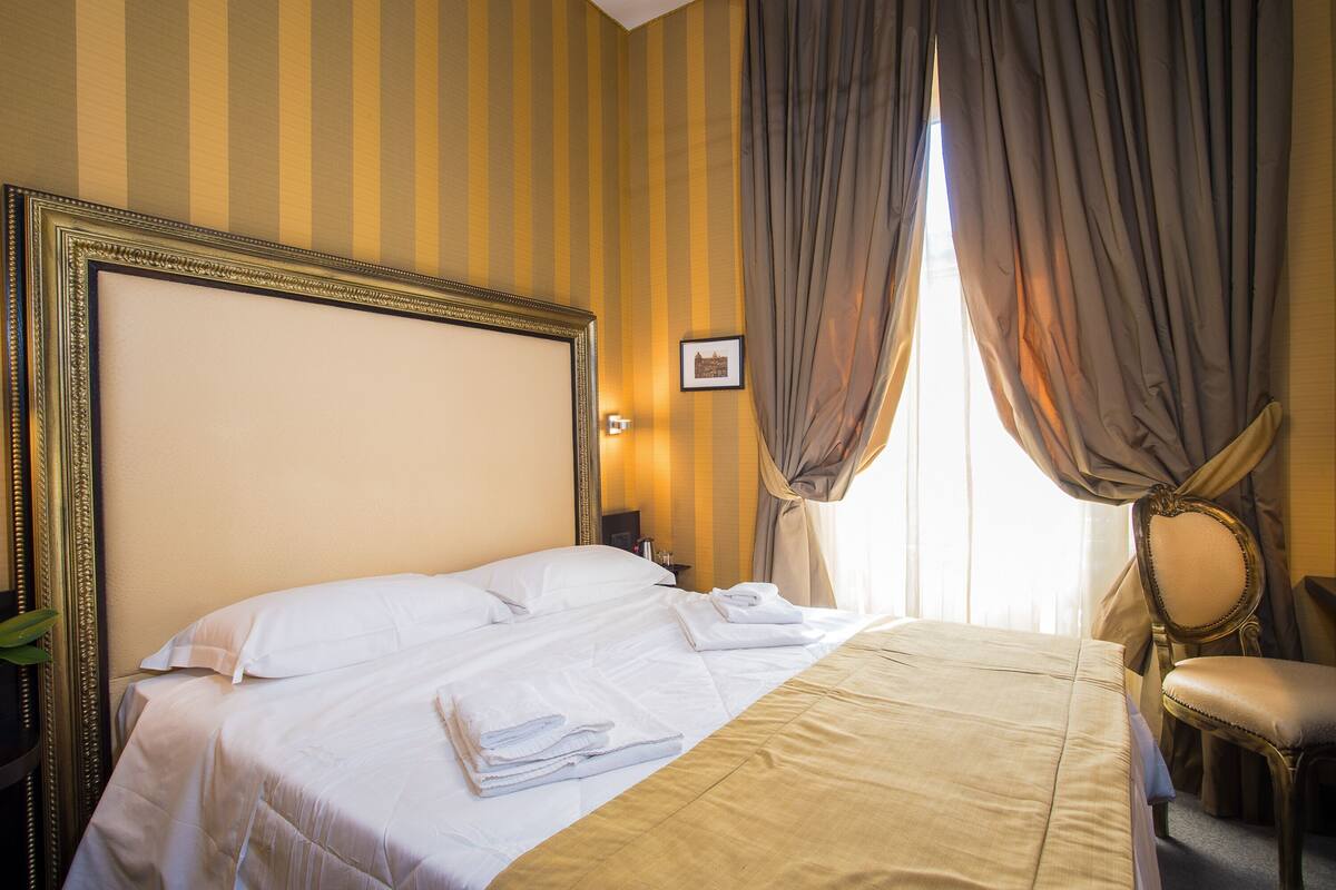 Ein Hotelzimmer mit einem großen Bett, einem Sessel, einem Nachttisch und einem Bild an der Wand.