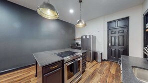 Eine moderne Küche mit Kochinsel, Edelstahlgeräten und dunklem Holzboden.