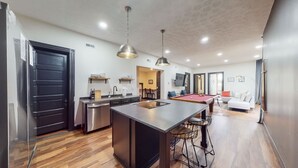 A modern kitchen with a central island, bar stools, a pool table, and a dining area with chairs. - Pool Table|King Beds|0.6 miles from UofL|Downtown (Louisville)
