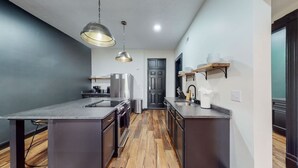 A modern kitchen with a central island, stainless steel appliances, and wooden flooring. - Pool Table|King Beds|0.6 miles from UofL|Downtown (Louisville)
