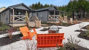A modern building with a grey exterior, wooden deck, and a covered outdoor seating area. - Seabrook Right as Rain | Pet Friendly, Cabin, 1BR | Sleeps 6, Fernwood (Pacific Beach)