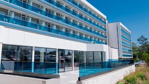 Un hotel de varios pisos con piscina, amplias ventanas y un diseño arquitectónico moderno.