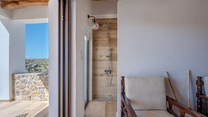 A modern bathroom with a wooden shower, a stone wall, and a view of the landscape. - Nomas  Skaloti House (Skaloti)