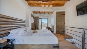 A bedroom with a large bed, wooden headboard, a wooden staircase, and a view of the outdoors. - Nomas  Skaloti House (Skaloti)
